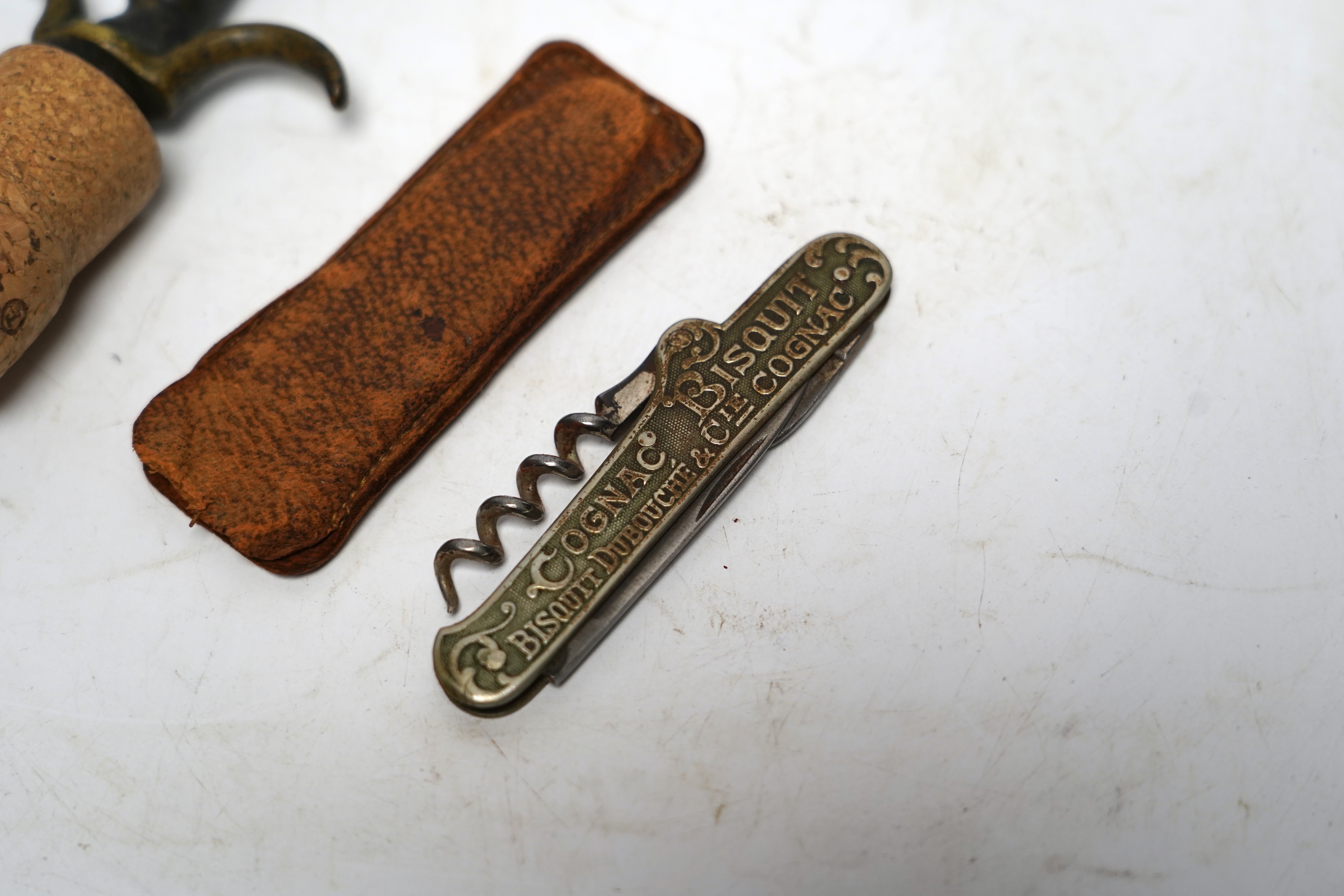 Two corkscrews; one advertising Jean E Sottiris-Le Caire, on reverse, Cognac Bisquit, Bisquit Du Bouche &Cie Cognac together with an ornate brass corkscrew largest 14cm